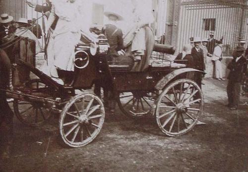 (Coche de caballos a delante de unas rejas)