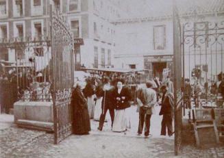 (Calle con mercado desde el interior de un recinto con rejas)