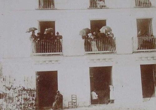 (Mujeres con paraguas asomadas en unos balcones)