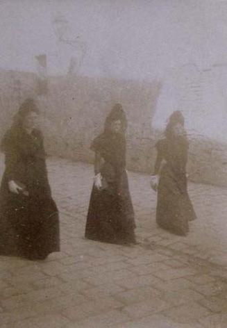 (Tres mujeres con mantilla andando por una calle)