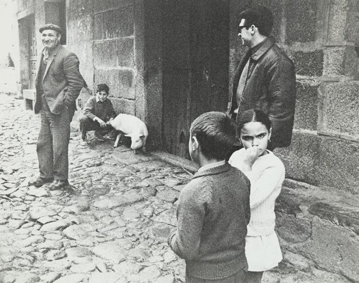 Grupo de personas y cerdo en la calle de un pueblo