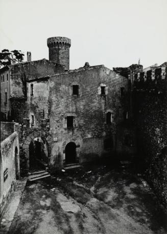 Plaza de un pueblo, con torre de castillo al fondo