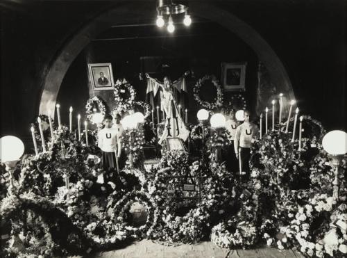 Conjunto de flores y cortejo fúnebre ante tumba