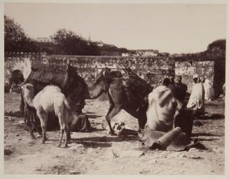 Grupo de personas y sus camellos junto a la puerta de una ciudad