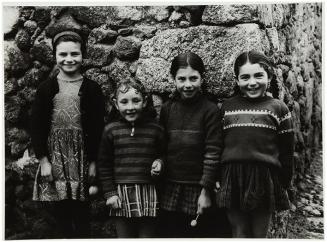 Cuatro niñas apoyadas en muro de piedra