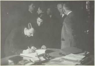 (Hombre firmando en el Llibre d´Or del Comissariat de Propaganda ante la mirada de Jaume Miravitlles)