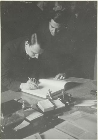 (Hombre firmando en el Llibre d´Or del Comissariat de Propaganda ante la mirada de Jaume Miravitlles)