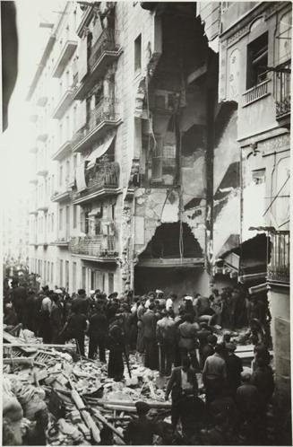 (Gente en una calle con una casa destruida en un bombardeo)