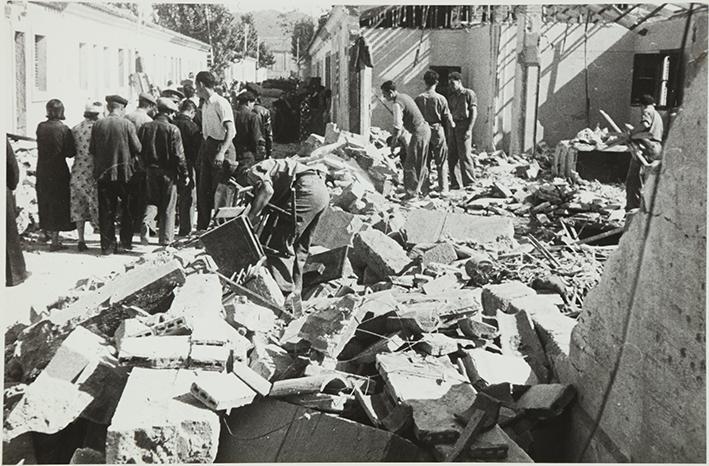 (Gente delante de un edificio destruido en un bombardeo)