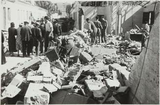 (Gente delante de un edificio destruido en un bombardeo)